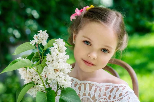 Beyaz leylak çiçekli küçük kız. — Stok fotoğraf