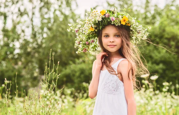 Menina sorridente bonito com coroa de flores no prado em th — Fotografia de Stock