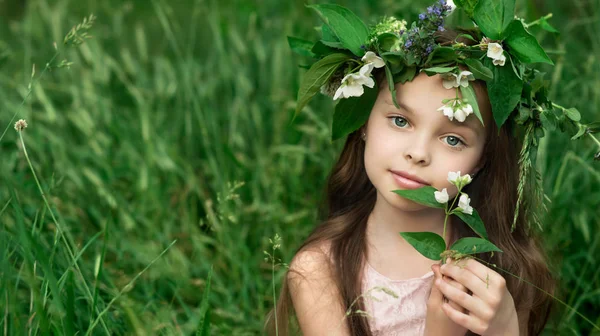 Vacker liten flicka i en vit klänning poserar i gräset — Stockfoto