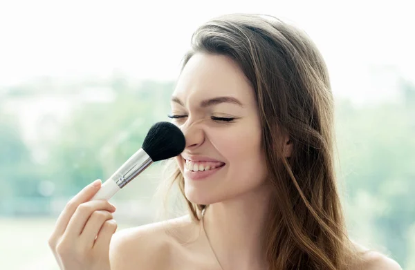 Menina bonita com escova de pó cosmético para maquiagem. — Fotografia de Stock