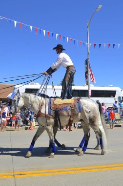 Kovboy ayağa kalkıp iki at sürmek