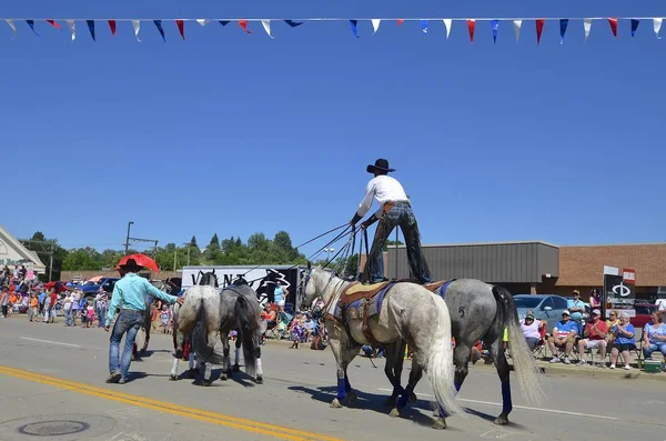 Cowboy in piedi su due cavalli a una parata — Foto Stock