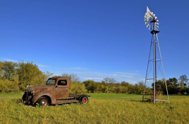 An old rusty pickup and a wind mill.  clipart