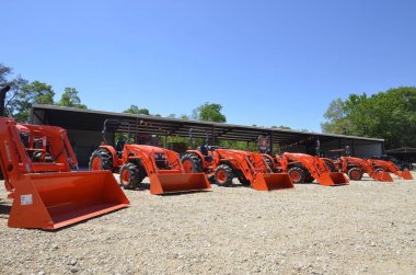 Line of orange Kubota tractors clipart