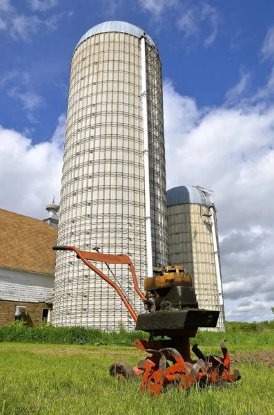 Velho cultivador de jardim oleoso e por celeiro e silos — Fotografia de Stock