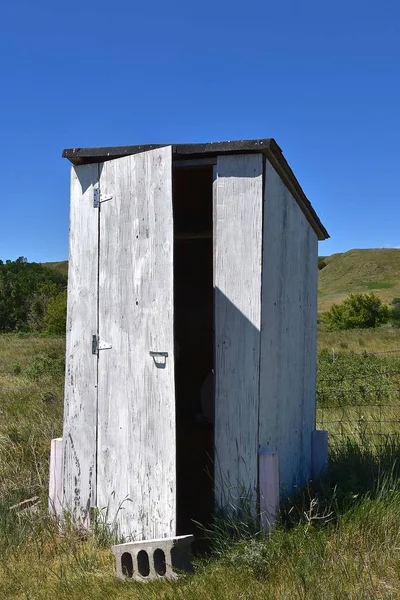 Puerta parcialmente abierta en una vieja letrina blanca — Foto de Stock