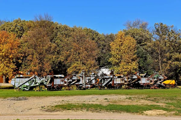 Serie av gamla tröskverk parkerad vid hösten färgade träd — Stockfoto