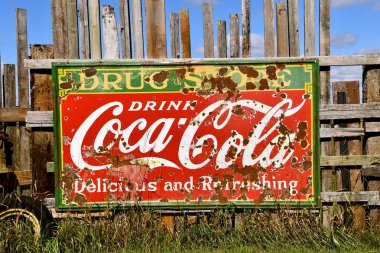 Eski Coca Cola işareti yıpranmış bir ağaç çit tarihinde gönderildi.