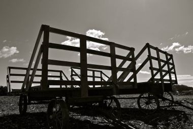 Gökyüzünü siluetli Çelik tekerlekler ile buğday ve yulaf demetleri taşıma için birkaç eski ahşap hayraf.