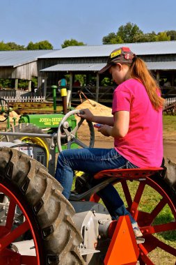 Rollag, Minnesota, 2 Eylül 2017: eski bir Farmall traktör geri ve iletişim kurmak için kullandığı bir tanımlanamayan genç bayan sürücülerde fuarında yıllık Wcstr çiftlik nerede 1000 katılmak her İşçi Bayramı hafta sonu düzenlenen Rollag cep telefonu.
