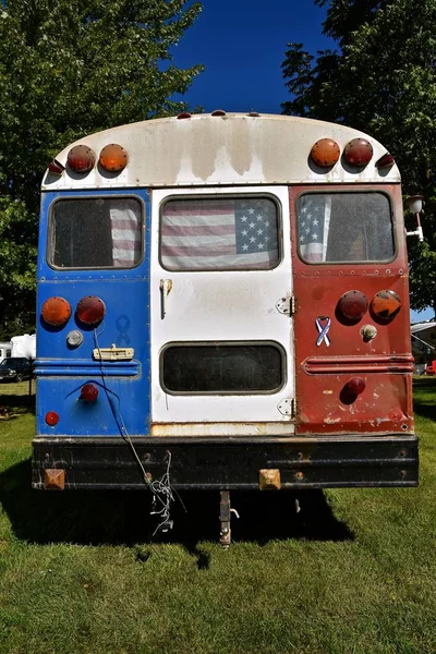 An old school bus has been painted red, white, and blue as it was converted into a patriotic camper.