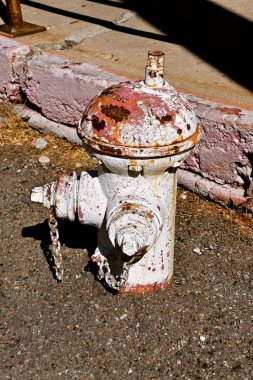 Eski bir yangın musluğu beyaz boyalı kırık kaldırım ve kirli sokak yakındır