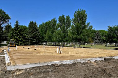 Yeni dökülen bir temel sıhhi tesisat hatları ile kum tabakası çevreleyen ve yerinde