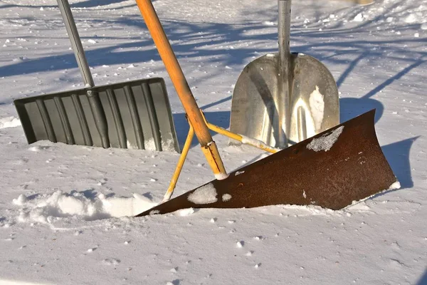 雪の中には雪を除去するための3種類のシャベルが埋葬されています — ストック写真