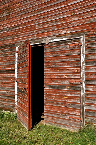 An open door to an old barn with red peeling paint