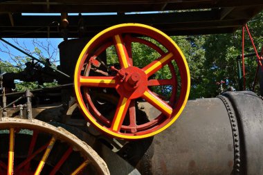Parlak boyalı bir çark buhar makinesine güç sağlar.. 