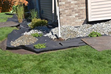 Yard rock is placed alongside the foundation of a house in a outside horticulture project. 