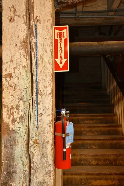 古い倉庫の地下にある看板は消火器の場所を示しています — ストック写真