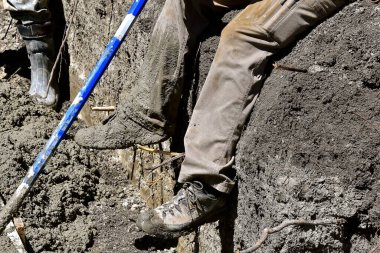Ayakkabısına ıslak çamur bulaşmış beton işçisi yeni bir inşaat sahasının temelinde çalışırken mola verir..