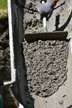 İnşaat alanındaki bir kamyondan aşağı ıslak beton dökülüyor..