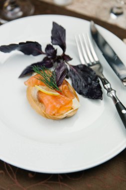 Bruschetta tereyağı, somon ve beyaz plaka üzerinde limon ile