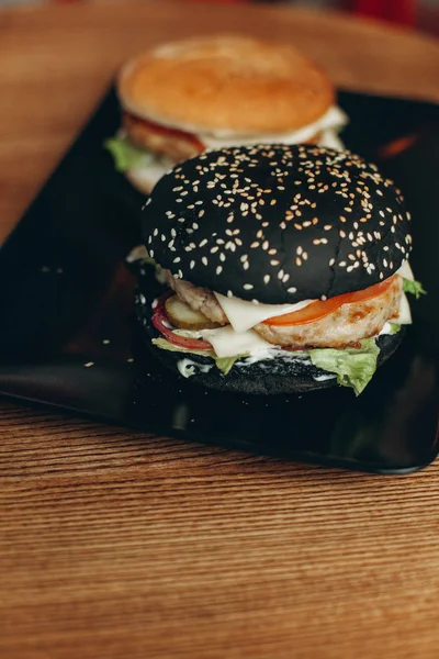 Czarny burger i regularnie burger na talerzu czarny — Zdjęcie stockowe