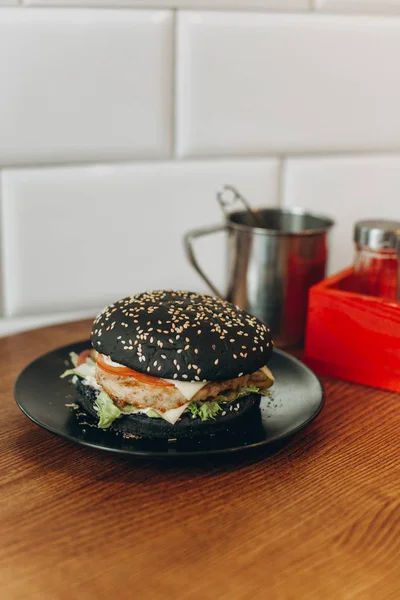 Hamburguesa negra con chuleta picada y tomates —  Fotos de Stock