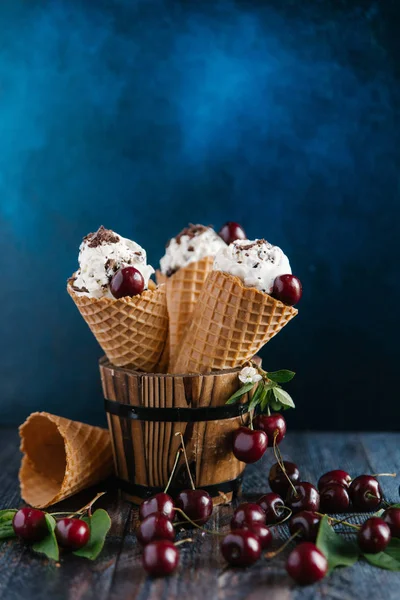 Waffle cones with ice cream and cherries