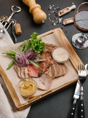 Çanak et iki soslar ile devam eder farklı türde yapılmış, salata yaprakları ve soğan dilimlenmiş ahşap tepsi