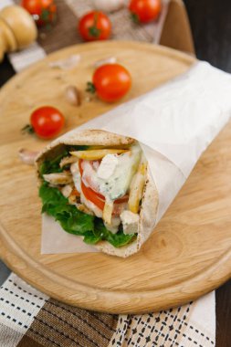Ahşap plaka ızgara shawarma parşömen kağıt arka plan bulanık üzerine sarılı ile görünümünü portre