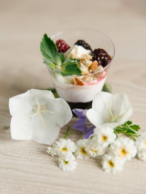 Yunan yoğurt böğürtlen reçeli ve fındık, nane ve böğürtlen ahşap yüzeyi çiçekler ile üst  