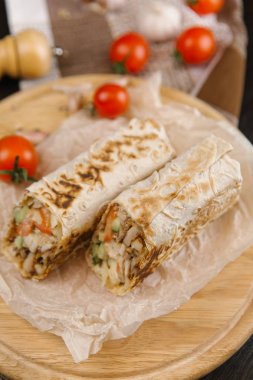 gevrek ve sulu shawarma iki adet yuvarlak ahşap plaka domates ile servis