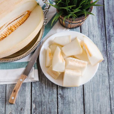 Natürmort bıçak, peçete ve vazo arka plan üzerinde beyaz tabakta servis taze kesilerek kavun ile