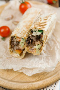 Domates ve arka plan bulanık yuvarlak ahşap plaka üzerinde ızgara shawarma