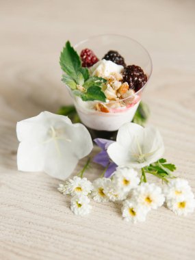 Yunan yoğurt böğürtlen reçeli ve fındık, nane ve böğürtlen ahşap yüzeyi çiçekler ile üst  