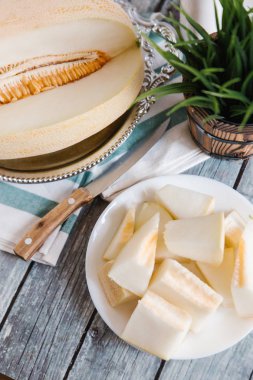 Yukarıdan kesilerek kavun ile bıçak, peçete ve vazo arka plan üzerinde beyaz tabakta servis