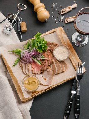 Çanak et iki soslar ile devam eder farklı türde yapılmış, salata yaprakları ve soğan dilimlenmiş ahşap tepsi