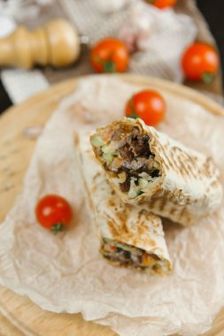 Domates ve arka plan bulanık yuvarlak ahşap plaka üzerinde ızgara shawarma