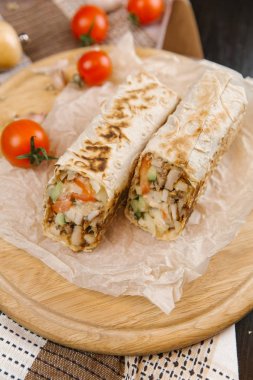 gevrek ve sulu shawarma iki adet yuvarlak ahşap plaka domates ile servis