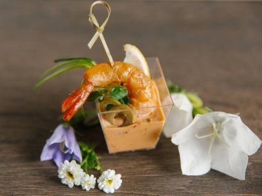 Cam vazo içinde tropikal sos ve arka plan üzerinde çiçekli zeytin ile servis şiş karides closeup görünümü