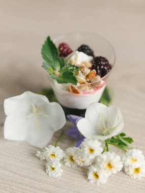 Yunan yoğurt böğürtlen reçeli ve fındık, nane ve böğürtlen ahşap yüzeyi çiçekler ile üst  