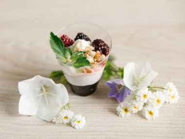 Yunan yoğurt böğürtlen reçeli ve fındık, nane ve böğürtlen ahşap yüzeyi çiçekler ile üst  