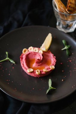 Humus Görünümü Kapat fındık ile tamamlanmaktadır, ayçiçeği tohumu, limon parça siyah plaka üzerinde germinated   