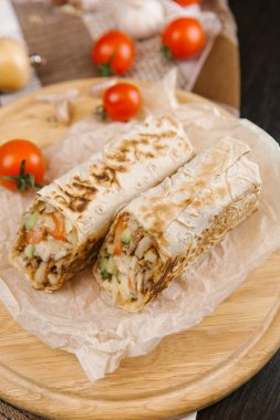 gevrek ve sulu shawarma iki adet yuvarlak ahşap plaka domates ile servis