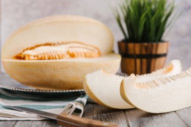 Metalik çanak üzerinde bıçak ve vazo arka plan üzerinde çizgili peçete ile servis kavun dilimli