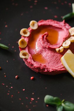 Humus Görünümü Kapat fındık ile tamamlanmaktadır, ayçiçeği tohumu, limon parça siyah plaka üzerinde germinated   