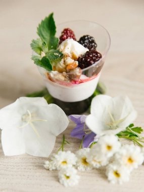 Yunan yoğurt böğürtlen reçeli ve fındık, nane ve böğürtlen ahşap yüzeyi çiçekler ile üst  