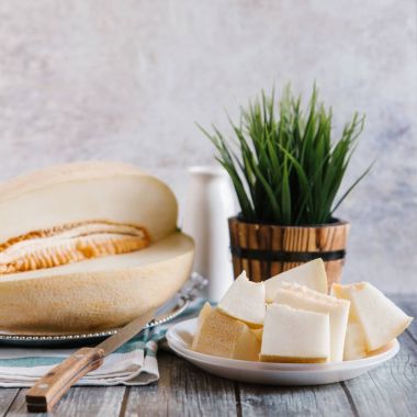 Bıçak, çizgili peçete, beyaz şişe ve yeşil vazo ile kesilerek kavun ile gıda kompozisyon 