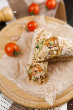 gevrek ve sulu shawarma iki adet yuvarlak ahşap plaka domates ile servis