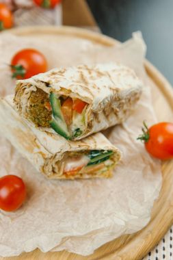 Domates, keten peçete ve arka plan bulanık ahşap plaka üzerinde ızgara shawarma